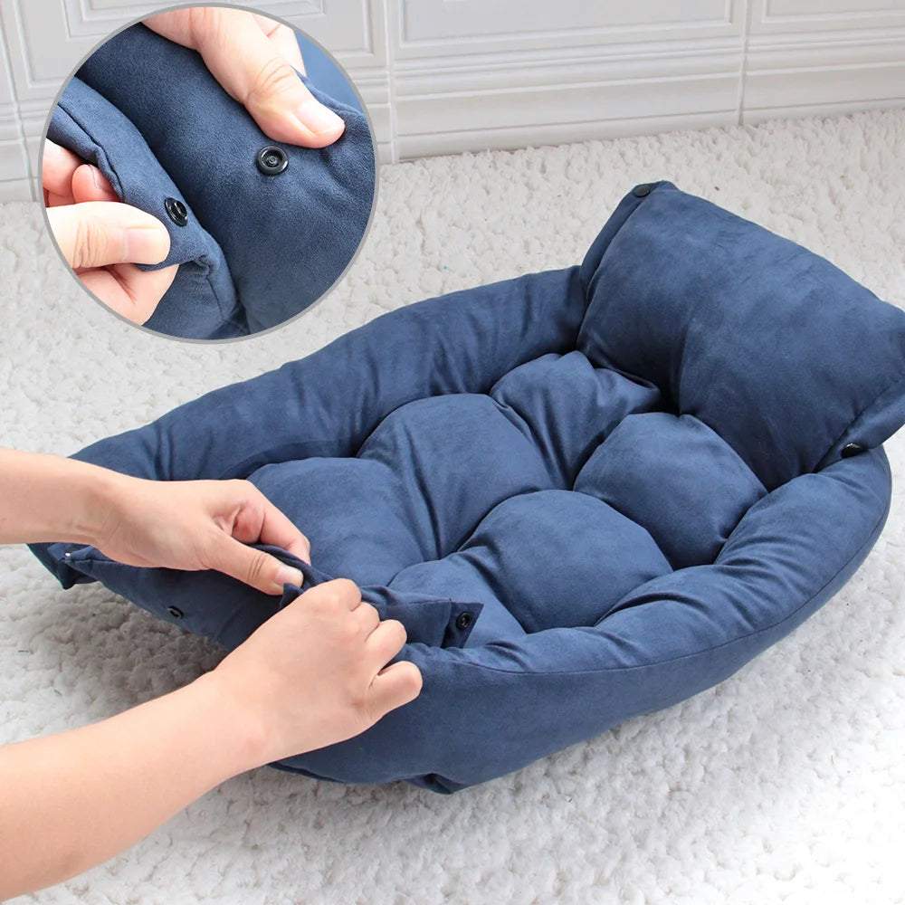 Blue pet bed with a hand adjusting it on a light gray floor.